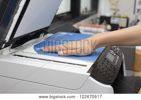 woman hands putting a sheet of paper into a copying device