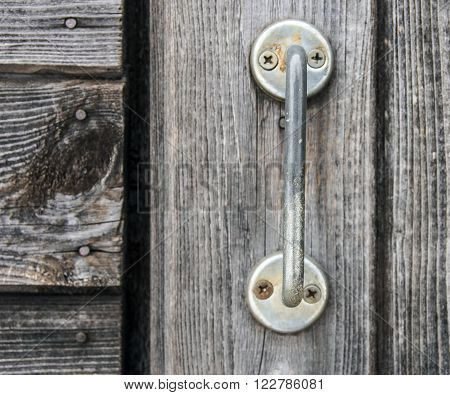 Metal handle on old grey wood door