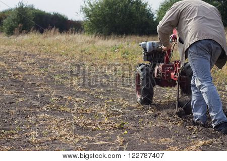 DIKANKA UKRAINE - SEPTEMBER 30 2015: Country farmer is plowing his garden with walk-behind garden tractorautumn field work