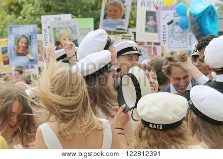 STOCKHOLM SWEDEN - JUN 10 2015: Group of happy teenages wearing graduation caps funny posters in the background celebrating the graduation after finishing high school at the school Globala gymnasiet June 10 2015 Stockholm Sweden