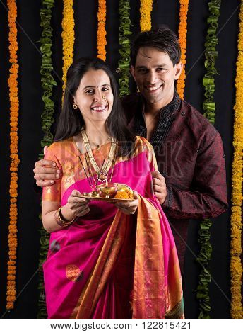 Portrait of Maharashtrian couple holding a puja thali, indian couple holding puja thali or pooja thali, indian couple celebrating diwali, laxmi pujan, asian couple and puja thali, couple doing prayer
