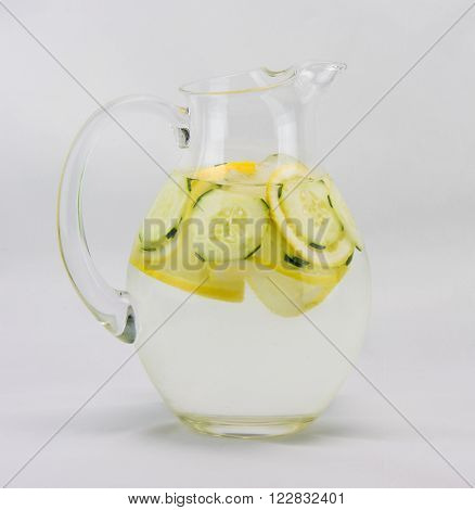 Pitcher of lemon, cucumber water set against a white background.