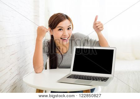 Woman showing blank screen of laptop computer with thumb up gesture