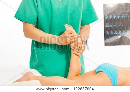 Massage therapist stretching kid's legs and foots at the massage cabinet