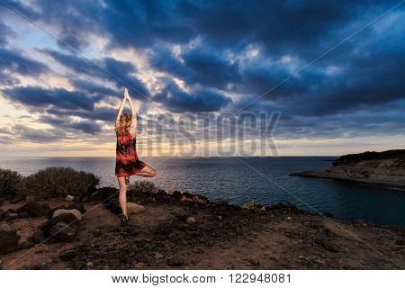 Summer sunset yoga session on beautiful Playa Fanabe beach - tropical Tenerife island Canary in Spain. Vriksha-asana tree pose