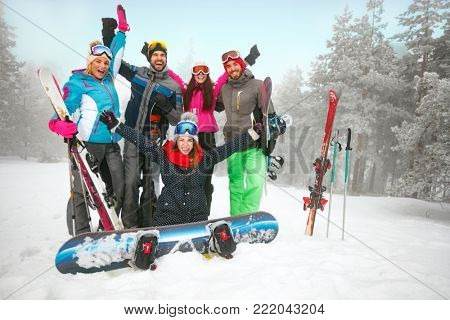 Group of cheerful friends skiers and snowboarders having fun on snowbound winter forest