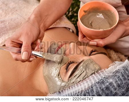 Facial mask for skin treatment. Mask of clay for mature skin. Face of woman of elderly woman 50-60 years old receiving cosmetic procedure in beauty salon close up .