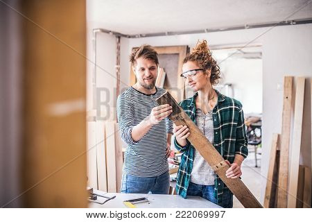 Small business of a young couple. Man and woman worker in the carpenter workroom.
