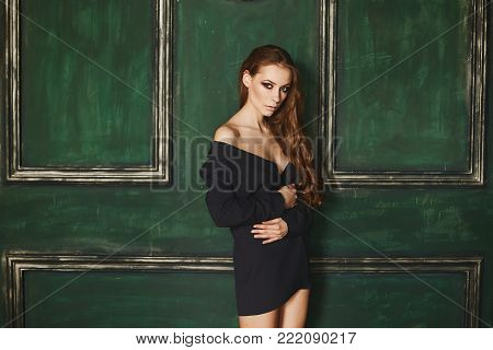 Beautiful half-naked brown-haired woman in the jacket in front of the darkgreen background.