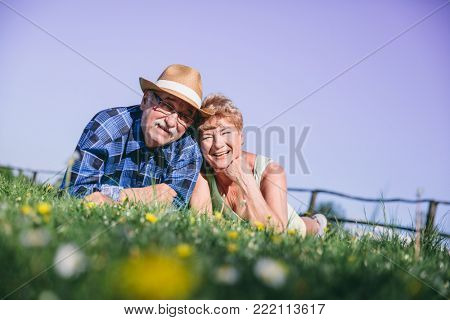 Senior couple laying on the grassfield, smiling. Happy mature couple.
