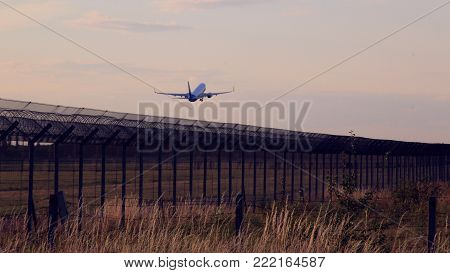 The plane jet takes off over safety airport fence at sunshine