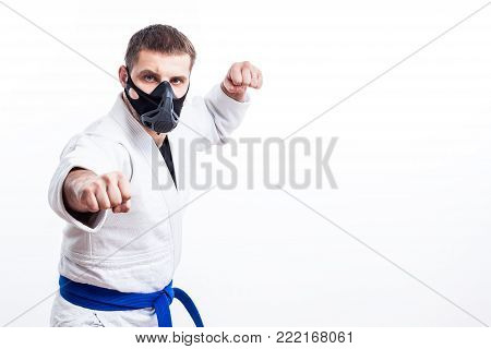 Young man fighter in a white kimono with blue belt for judo, jujitsu pose on isolated white background