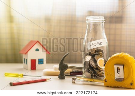A photo of coin in glass bottle with capenter tool, Saving for new home concept
