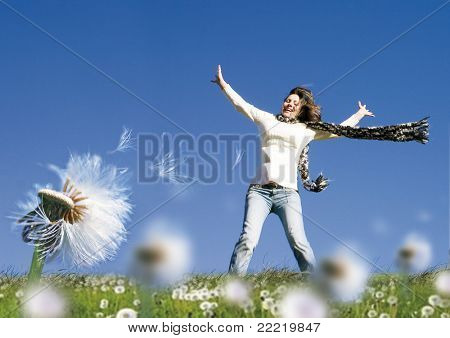dívka stojící na louce s pampelišky, vítr fouká