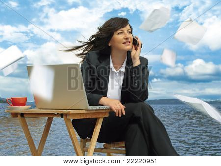 businesslady avec ordinateur portable fonctionne à côté d'un lac. Papier vole autour. Mot clé unique pour ce c