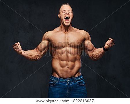 Studio portrait of shirtless muscular male in a jeans over grey background.