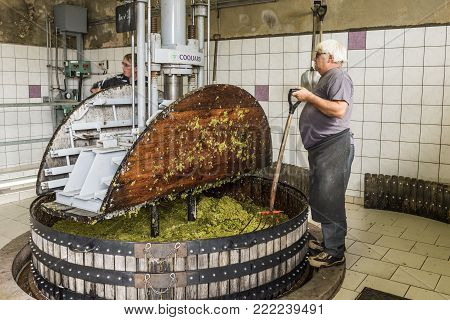 Hautvillers, France - August 11, 2017. Pressing the grapes with an old press with two working men in the Pressoir in Champagne village Hautvillers near Reims and Epernay.