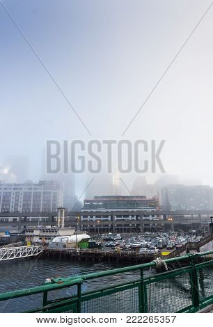 A foggy, portrait formatted image of an early morning city skyline and harbor