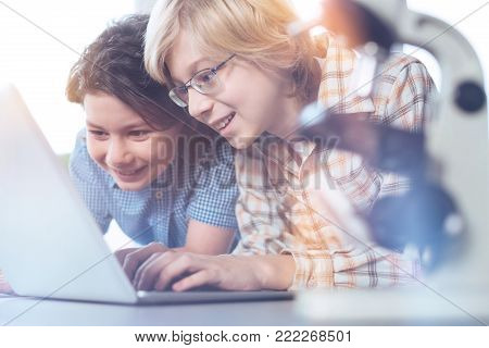 Just look at that. Enthusiastic quick witted inspired students searching for some data using a laptop and finding an exciting article on needed subject