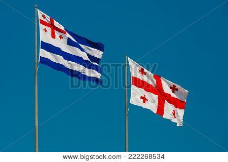 Large waving flag autonomous republic of Adjara and flag of Georgia, also known as the Five Cross Flag against the blue sky, Batumi, Adjara, Georgia