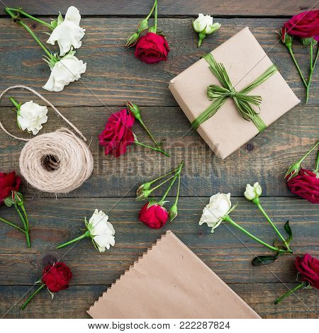 Pattern with roses, gift box, craft paper and twine on wood background. Workspase. Flat lay, top view. Woman background