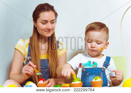 kid with mother color eggs for easter together