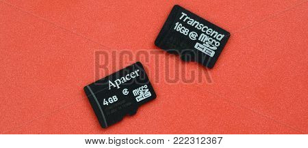 KHARKOV, UKRAINE - DECEMBER 29, 2017: Two small micro SD memory cards Apacer 4gb and Transcend 16gb lies on a red background. Illustrative editorial