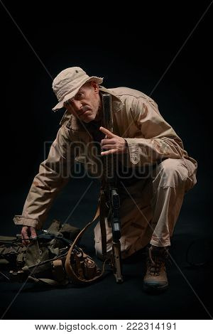 special forces soldier of the united states poses with a rifle on a black background