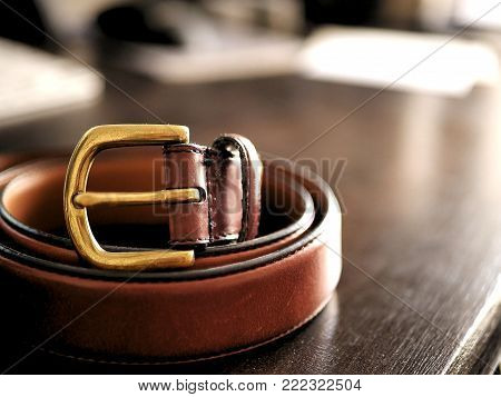 Brown Leather Belt on Wooden Desk with Bokeh