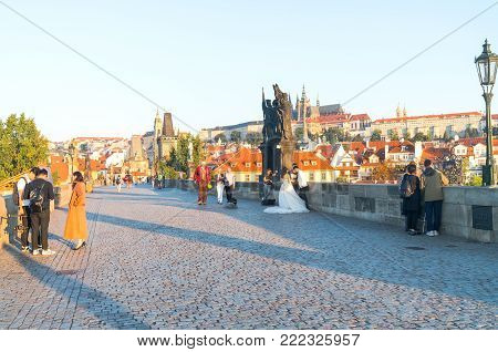 PRAGUE CZECH REPUBLIC - AUGUST 29,2017;  Charles Bridge at sunrise a few tourists and wedding group arrive to photgraph the historic area.