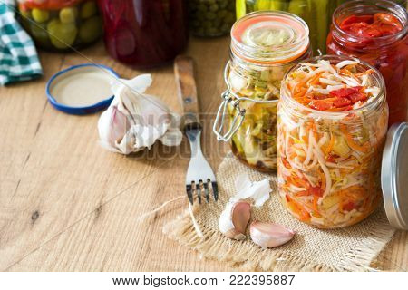 Fermented preserved vegetables in jar on wooden table. Copyspace