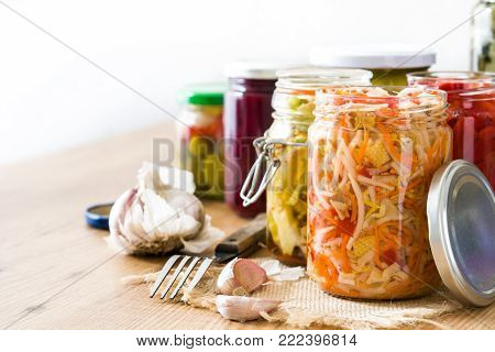 Fermented preserved vegetables in jar on wooden table. Copyspace