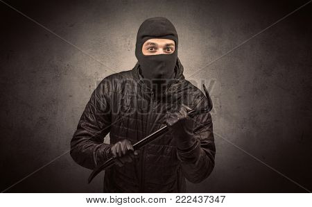 Burglar standing in black clothes and balaclava on his head.