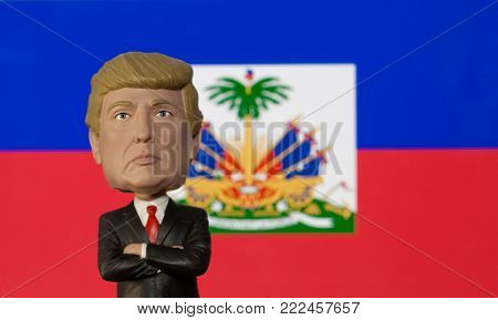 NEW JERSEY, USA - JAN 13 2018: Bobblehead caricature of US President Donald Trump standing in front of a Haitian flag