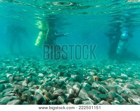 Jordan, Akaba - December, 25, 2017: Divers deep under water near the shore on the pebbles