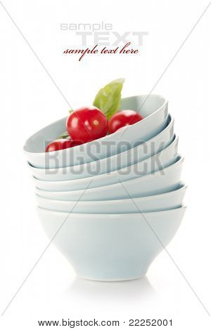 Pila di ciotole e pomodori freschi sopra bianco (con testo di esempio)