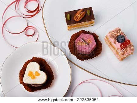 Delicious cupcake for Valentine Day and red ribbon on white plate. Valentines day background, table place setting. Mother's, Women's, Wedding Day concept.