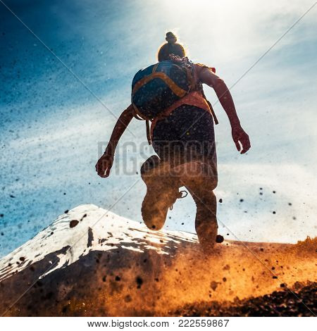 Woman athlete runs on a dirty and dusty ground with volcano on the background. Trail running athlete working out in the mountains