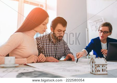 Young family couple purchase rent property real estate . Agent giving consultation to man and woman. Signing contract for buying house or flat or apartments. Discussion of size