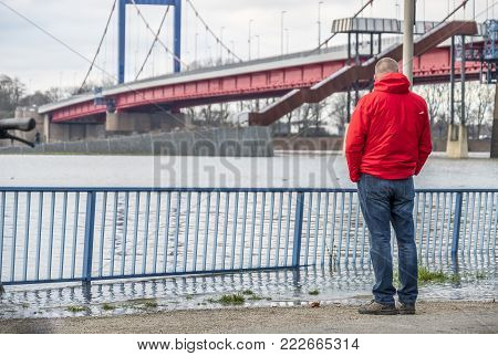 DUISBURG , GERMANY - JANUARY 08 2017 : Tourist observing the the river Rhine flooding the promenade and streets in Ruhrort