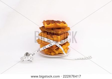 a stack of waffles on a white plate with measuring tape around them on white background