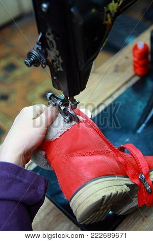 in a Shoe shop shoemaker sews on the sewing machine lock-on boots