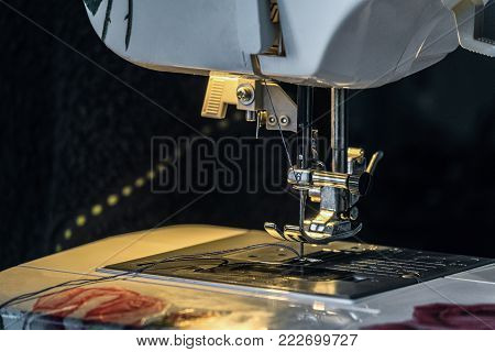 Steel needle with looper and presser foot of the sewing machine. Light of the built-in hardware lamp.