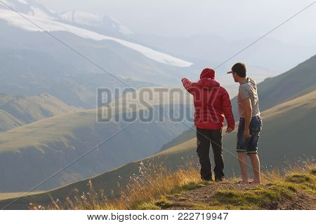 Guide pointing the way to the mountain. Unrecognizible people.