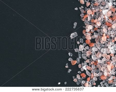Himalayan pink salt in crystals on black stone background. Copy space