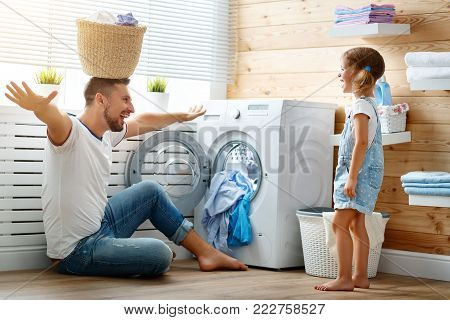 Happy family man father  householder and child daughter in laundry with washing machine
