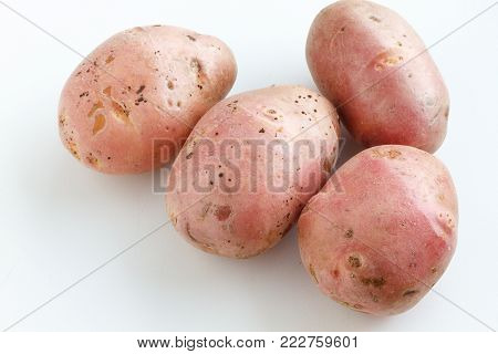 A lot of dirty potatoes on a white background. Potatoes scattered on a white background.