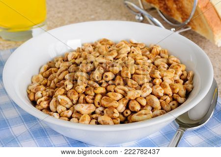 Honey coated puffed wheat breakfast cereal in a breakfast setting with toast and juice