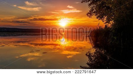 majectic sunset over the lake. overcast clouds in the sky , gloving in sunlight. picturesque dramatic scene. beauty in the world.
