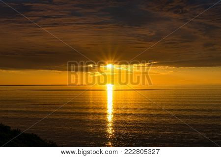 Spectacular sunset over sea with vivd golden colores of water and sky. Nature background